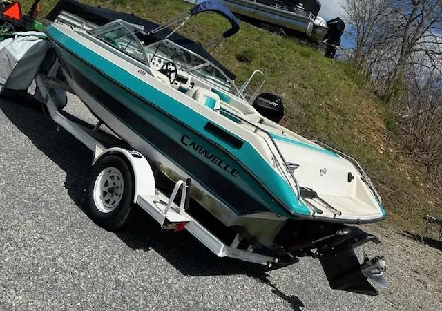 Slide: The Image of 1992 Caravelle 2000 boat on trailer, teal and white design, parked outdoors. - 3
