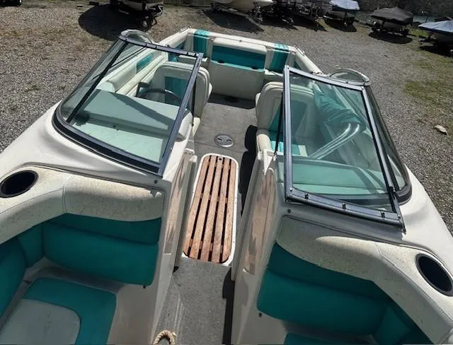 Slide: The Image of 1992 Caravelle 2000 boat with teal seating and open windshield, parked on gravel. - 9