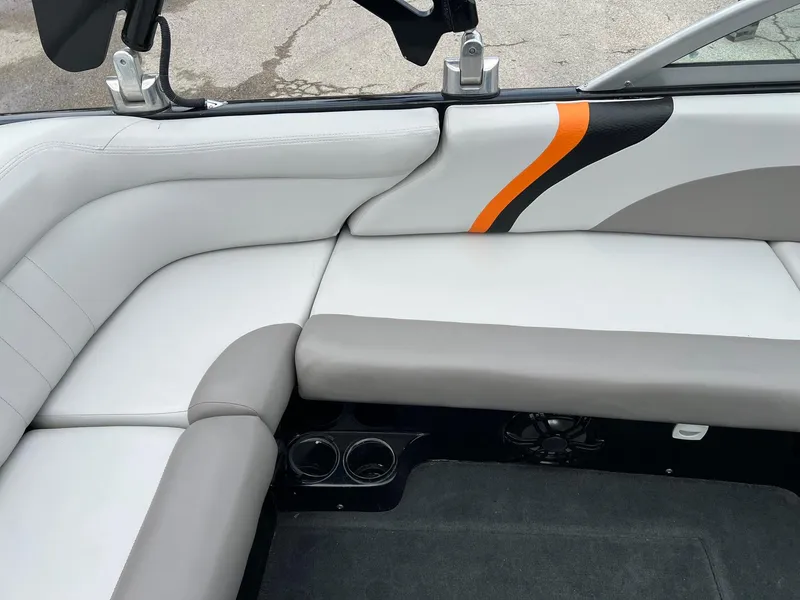 Slide: The Image of 2006 MasterCraft X1 boat interior with gray and white seating, orange accent, and cup holders. - 10