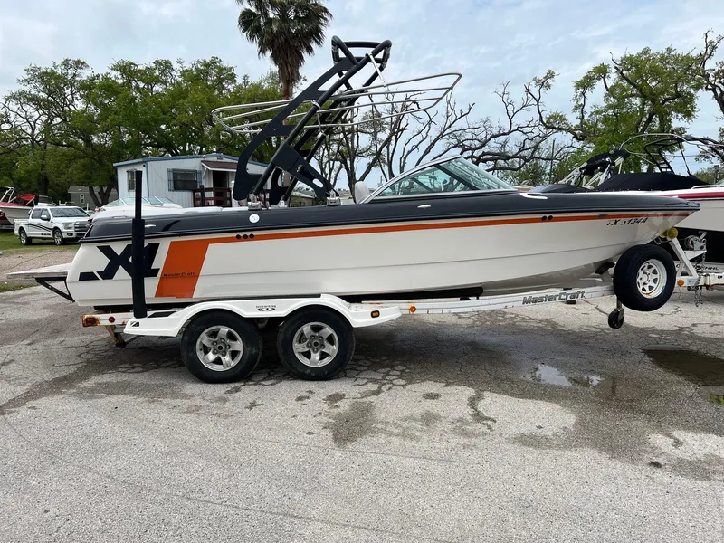 Slide: The Image of 2006 MasterCraft X1 boat on trailer, parked outdoors, featuring sleek design and vibrant orange accents. - 4