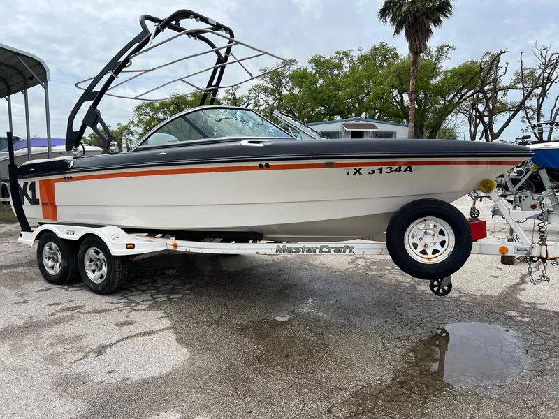 Slide: The Image of 2006 MasterCraft X1 boat on trailer, parked outdoors, with wakeboard tower and orange accents. - 6