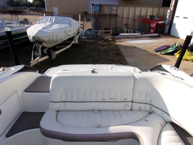 Slide: The Image of 2004 Cobalt 240SD boat interior with white seating, parked near covered boat and equipment. - 13