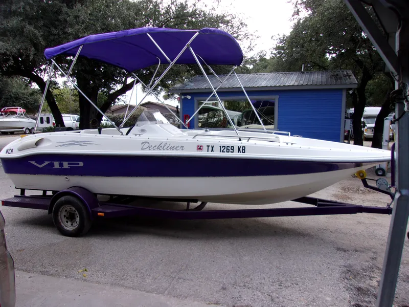 Slide: The Image of 2004 VIP Deckliner 191 boat with purple canopy on trailer, parked near blue building. - 2