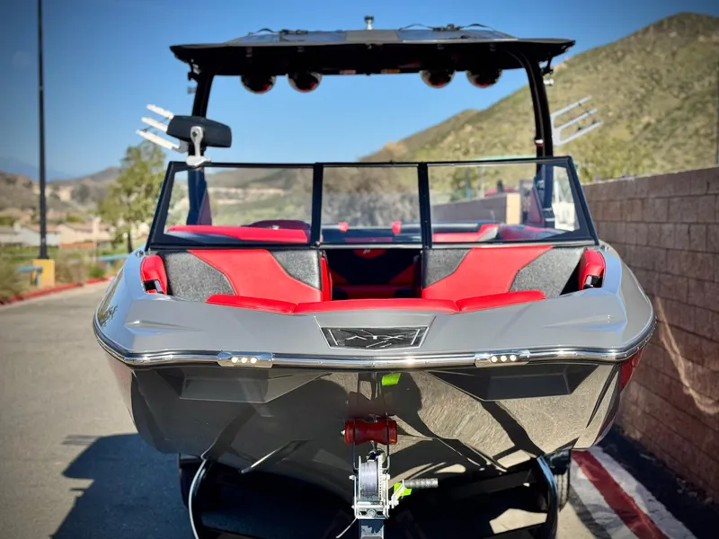 Slide: The Image of 2022 Tigé ATX 24 Type s boat with red and gray interior, parked outdoors. - 2