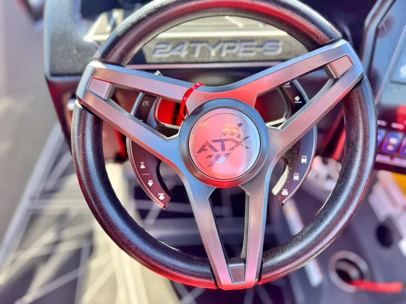 Slide: The Image of Steering wheel of 2022 Tigé ATX 24 Type s boat, featuring sleek design and logo. - 36