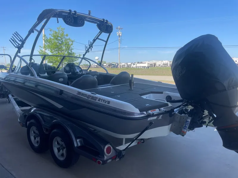 Slide: The Image of 2014 Ranger 211 VS boat with outboard motor on a trailer, parked outdoors. - 7