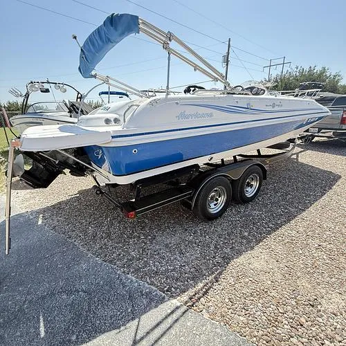 Slide: The Image of 2012 Hurricane 201 Sundeck Sport boat on trailer, blue and white design, parked outdoors. - 11
