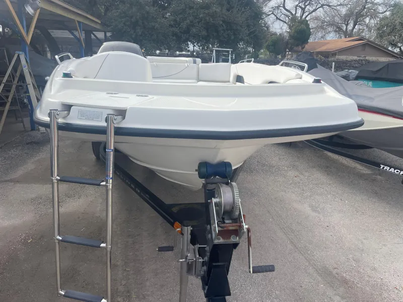 Slide: The Image of 2011 Bayliner 197 boat on trailer with ladder, parked outdoors. - 10