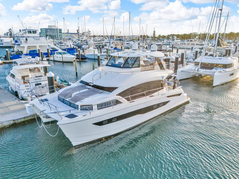 Slide: The Image of 2023 Aquila 54 Yacht docked, reflecting on calm water, surrounded by tropical greenery. - 108