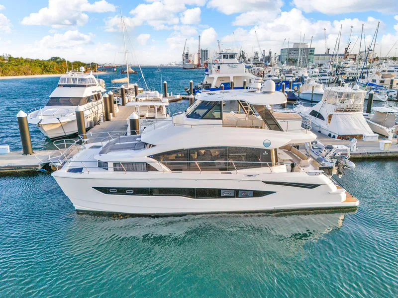 Slide: The Image of 2023 Aquila 54 Yacht docked in a serene waterfront setting with lush greenery. - 110