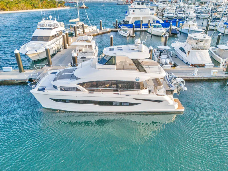 Slide: The Image of 2023 Aquila 54 Yacht docked near palm trees and waterfront homes. - 111