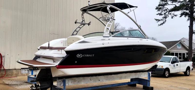 Slide: The Image of 2011 Cobalt 242 boat on a trailer, black and white design, parked outdoors. - 0
