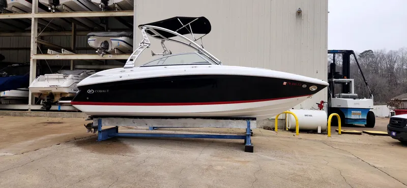 Slide: The Image of 2011 Cobalt 242 boat on a stand, black and white design, outdoor storage area. - 1