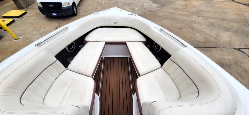 Slide: The Image of 2011 Cobalt 242 boat interior with white cushioned seating and wooden flooring. - 10