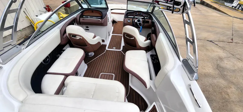 Slide: The Image of 2011 Cobalt 242 boat interior with white and brown seating, wood flooring, and steering console. - 9