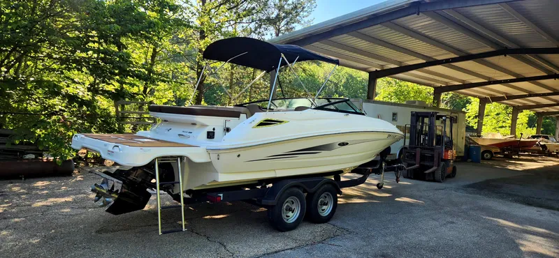 Slide: The Image of 2017 Sea Ray SDX 220 boat on trailer under canopy, surrounded by trees. - 2