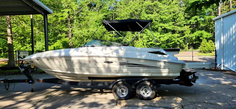 Slide: The Image of 2017 Sea Ray SDX 220 boat on trailer, parked outdoors with lush green trees in the background. - 5