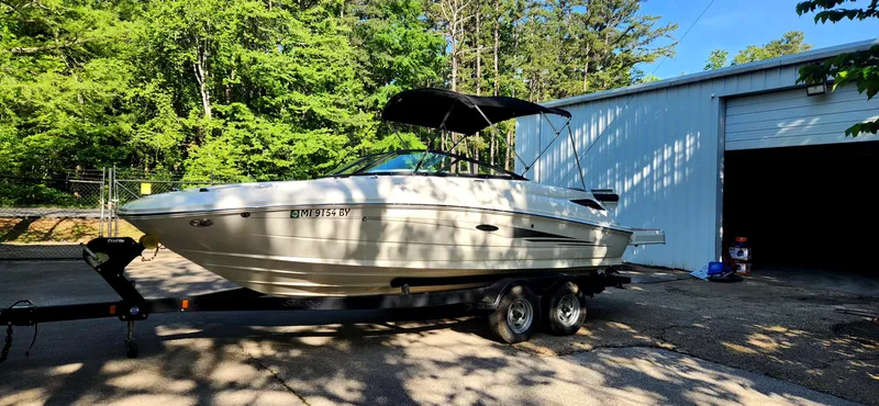 Slide: The Image of 2017 Sea Ray SDX 220 boat on trailer, parked near a garage, surrounded by trees. - 6
