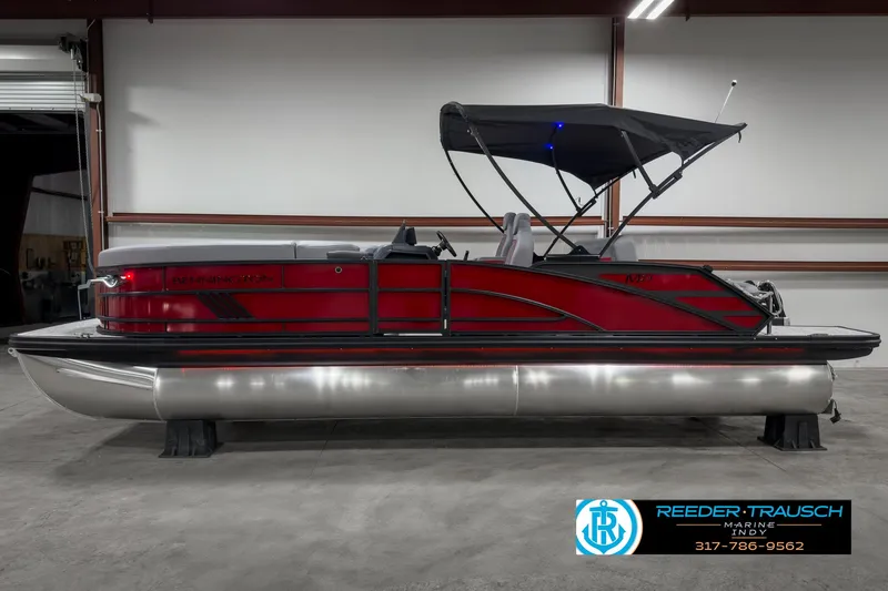 Slide: The Image of 2025 Bennington 24 MSB pontoon boat with red exterior and black canopy in a showroom. - 5