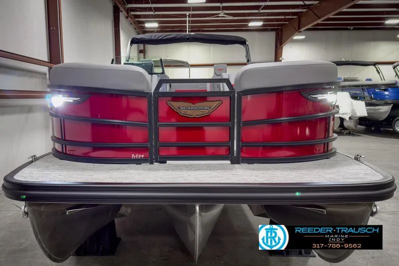 Slide: The Image of 2025 Bennington 24 MSB pontoon boat in a showroom, featuring a sleek red design. - 8