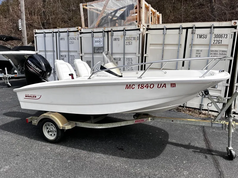 The Image of 2017 Boston Whaler 130 Super Sport boat on trailer, parked near shipping containers. - 0