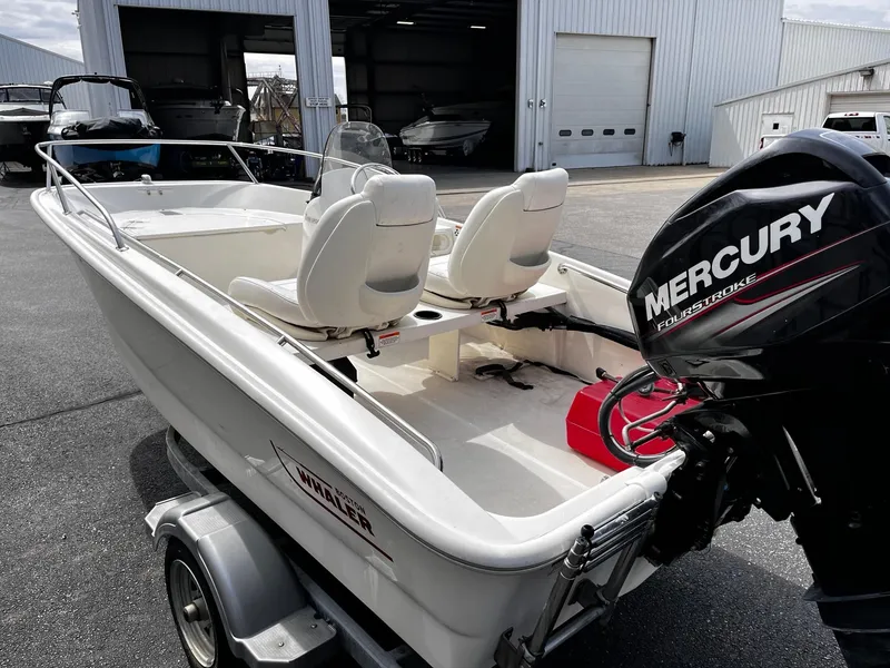 Slide: The Image of 2017 Boston Whaler 130 Super Sport boat with Mercury engine, parked outside a garage. - 2