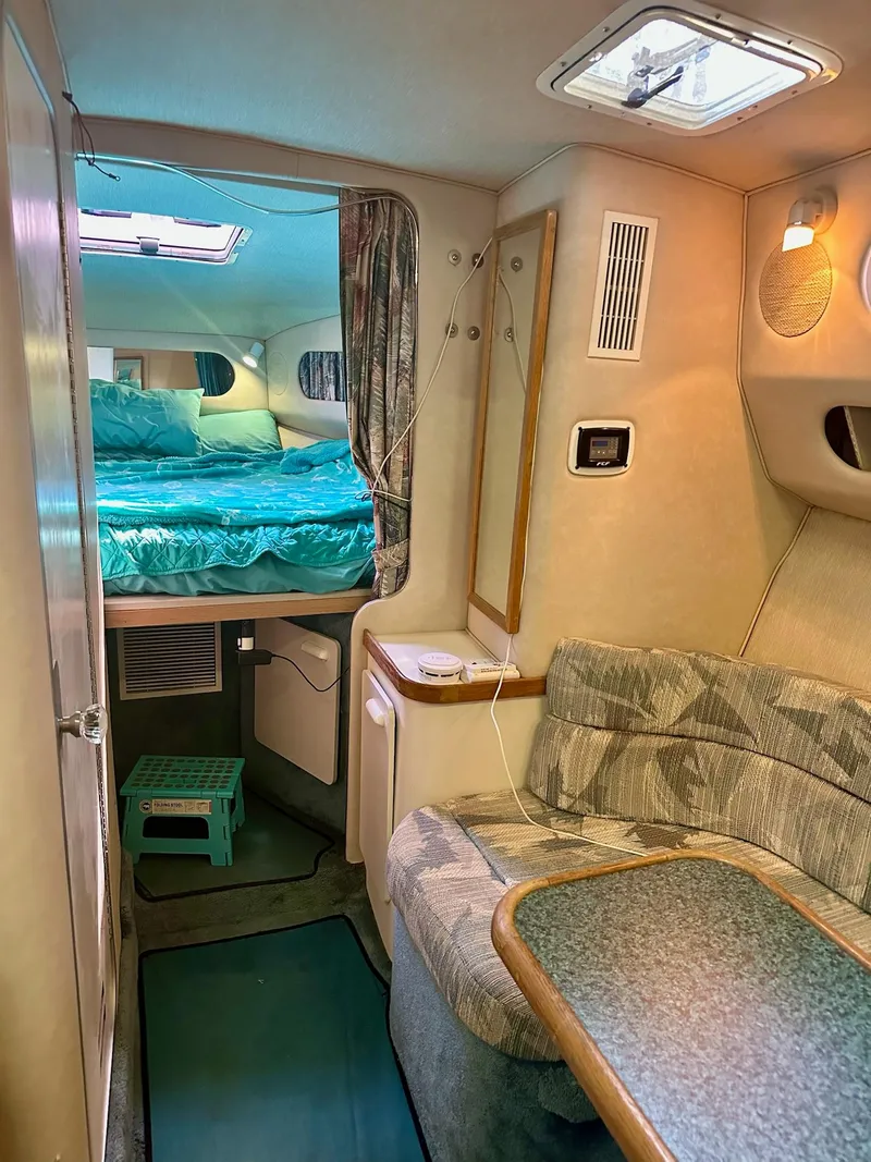 Slide: The Image of 1995 Sea Ray Sundancer cabin interior with bed, seating area, and natural light. - 13