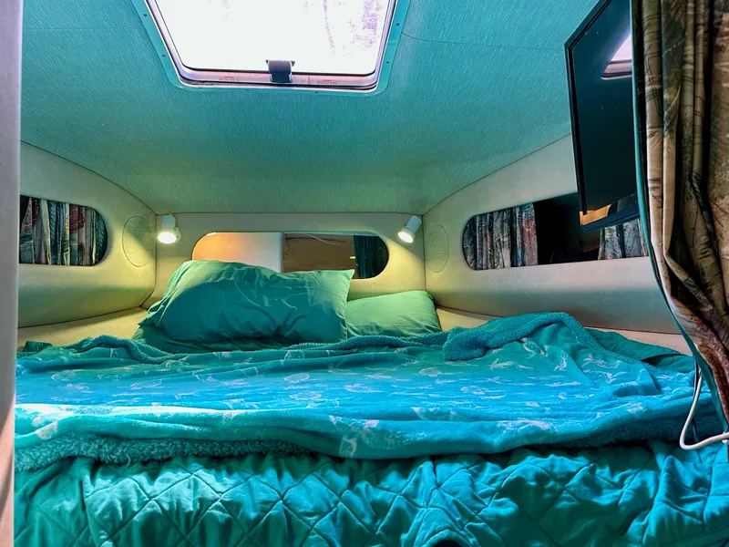 Slide: The Image of Cozy cabin interior of 1995 Sea Ray Sundancer with teal bedding and overhead lighting. - 16