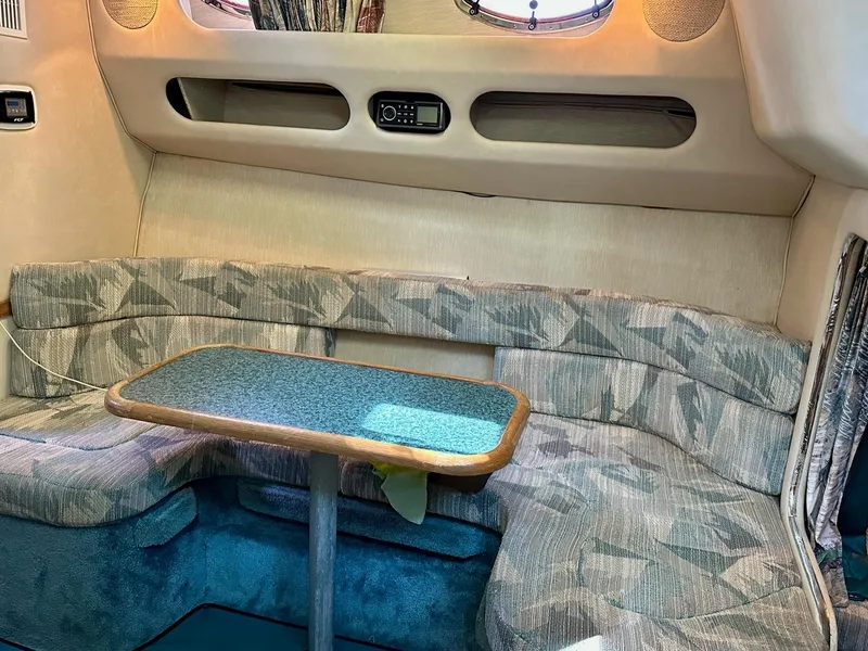 Slide: The Image of Interior of a 1995 Sea Ray Sundancer with cushioned seating and a small table. - 18