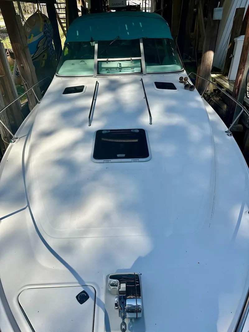 Slide: The Image of 1995 Sea Ray Sundancer boat with teal canopy, docked in a shaded area. - 3