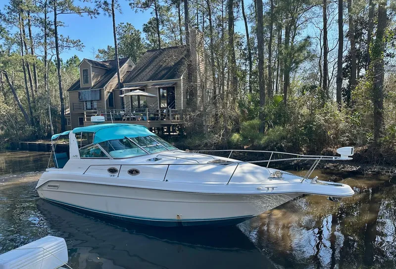 Slide: The Image of 1995 Sea Ray Sundancer boat docked near a rustic cabin in a wooded area. - 4