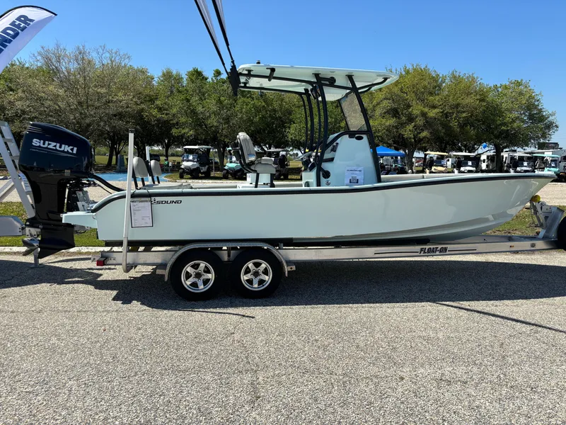 Slide: The Image of 2024 Clark Sound 24 boat on trailer with Suzuki outboard motor, parked outdoors. - 4