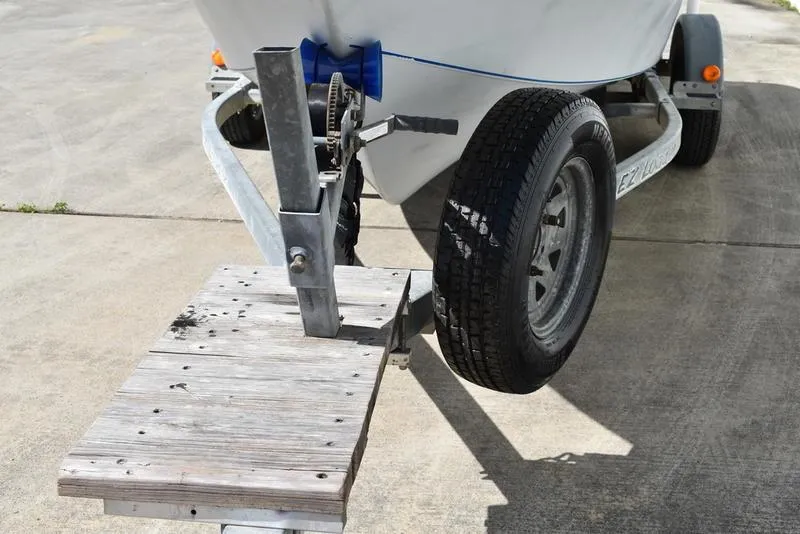 Slide: The Image of Trailer hitch and wheel of a 1996 Kenner 16v boat on concrete surface. - 8