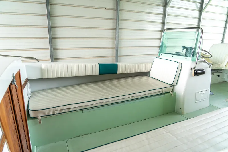 Slide: The Image of 1976 Aquasport 24 Launch interior with cushioned seating and steering console in a covered area. - 12