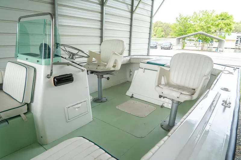 Slide: The Image of 1976 Aquasport 24 Launch boat interior with white seating and green flooring in a covered area. - 13