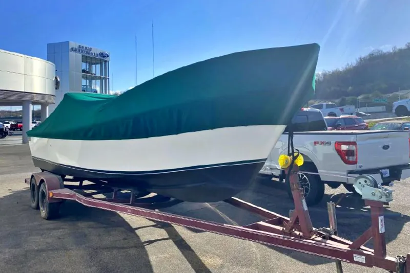 Slide: The Image of 1976 Aquasport 24 Launch boat on trailer, covered, parked near dealership. - 3