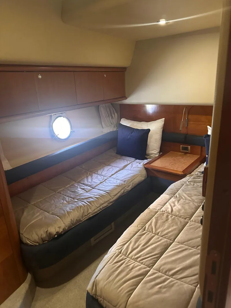 Slide: The Image of 2007 Azimut 55E yacht cabin with twin beds and wooden accents. - 8