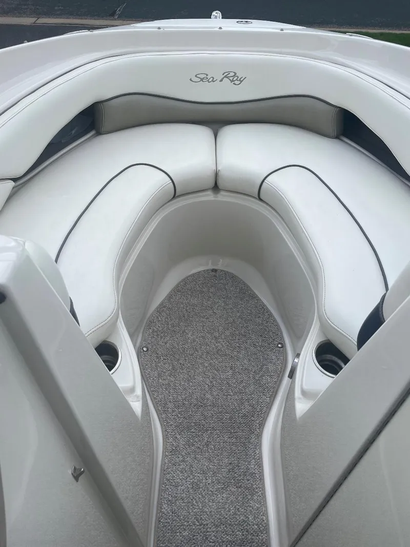 Slide: The Image of 2007 Sea Ray 210 Select boat interior with white cushioned seating and carpeted floor. - 2