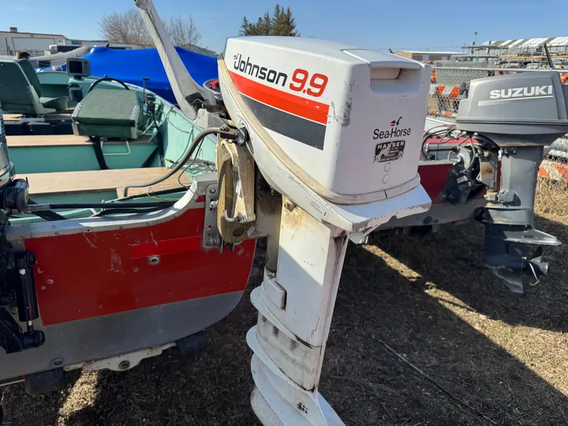 Slide: The Image of 1979 Lund L boat with Johnson 9.9 Seahorse outboard motor, parked outdoors. - 1