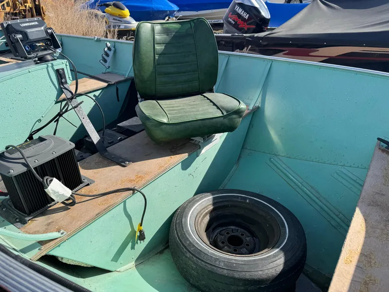 Slide: The Image of 1979 Lund L boat interior with green seat, spare tire, and electronic equipment. - 10