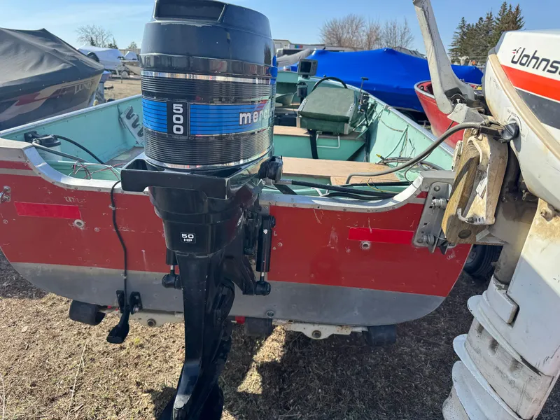 Slide: The Image of 1979 Lund L boat with Mercury 500 outboard motor, parked outdoors. - 2