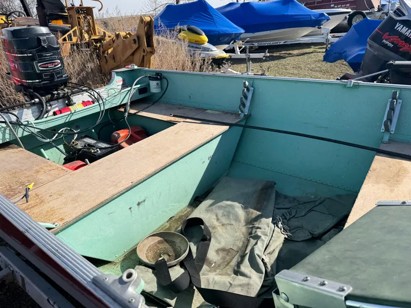 Slide: The Image of 1979 Lund L boat interior with motor, parked outdoors among other covered boats. - 5