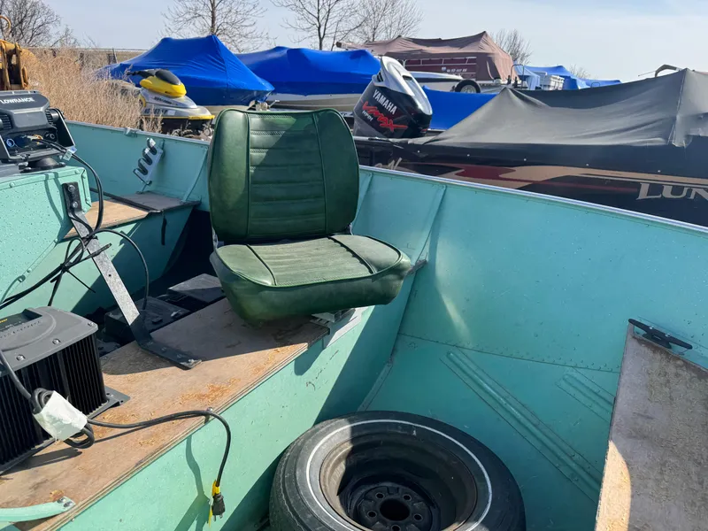 Slide: The Image of 1979 Lund L boat interior with green seat and equipment, parked outdoors. - 8