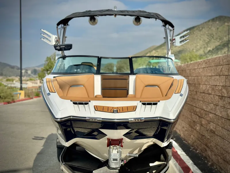 Slide: The Image of 2022 MasterCraft XStar boat with tan seating, parked on a sunny day. - 2