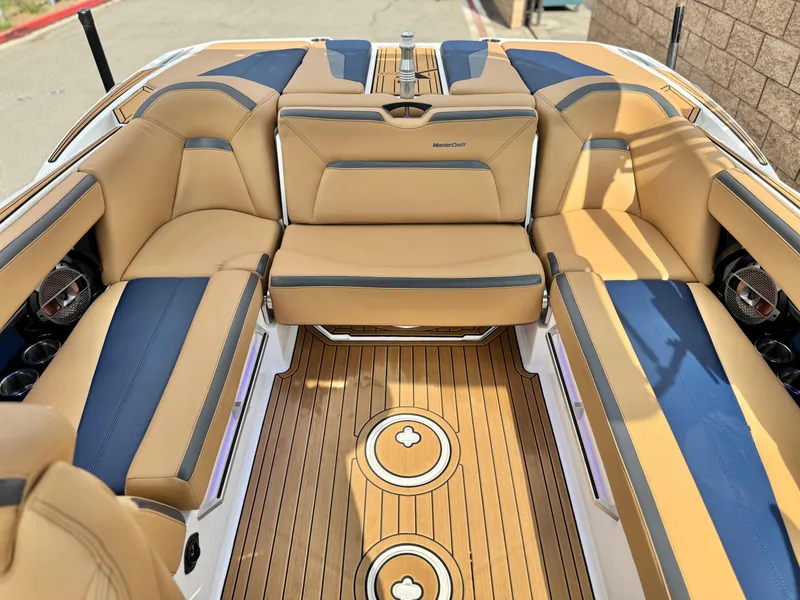 Slide: The Image of 2022 MasterCraft XStar boat interior with tan and blue seating, teak flooring. - 20