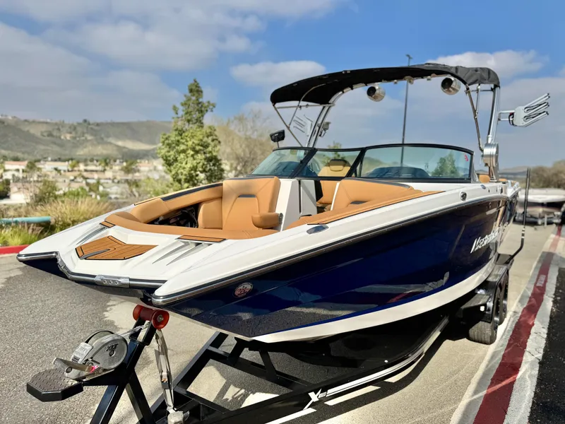Slide: The Image of 2022 MasterCraft XStar boat on trailer, blue and white with tan interior, parked outdoors. - 3