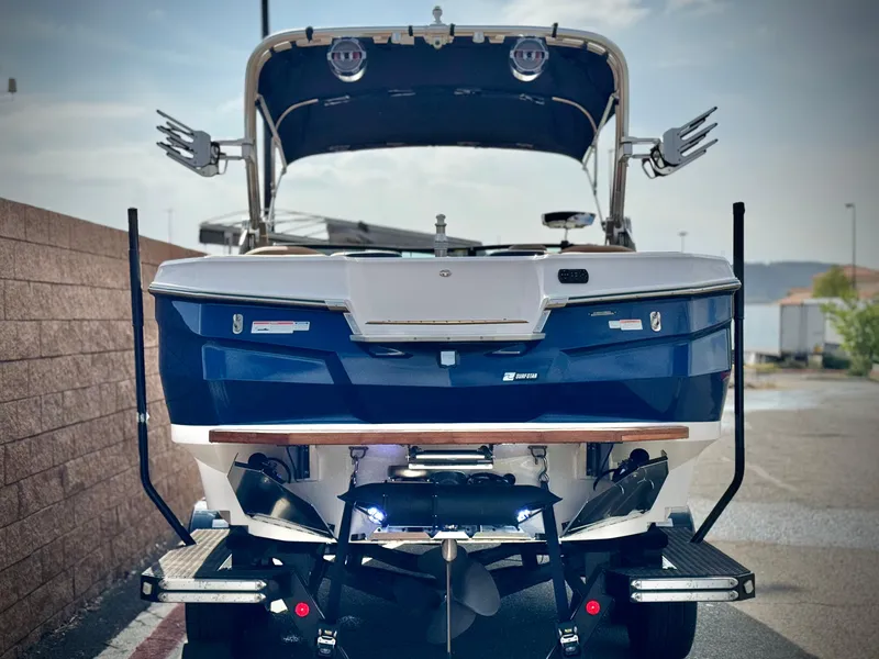 Slide: The Image of 2022 MasterCraft XStar boat, rear view, blue and white design, parked outdoors. - 4