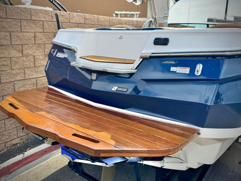 Slide: The Image of 2022 MasterCraft XStar boat with wooden swim platform, blue and white exterior. - 6