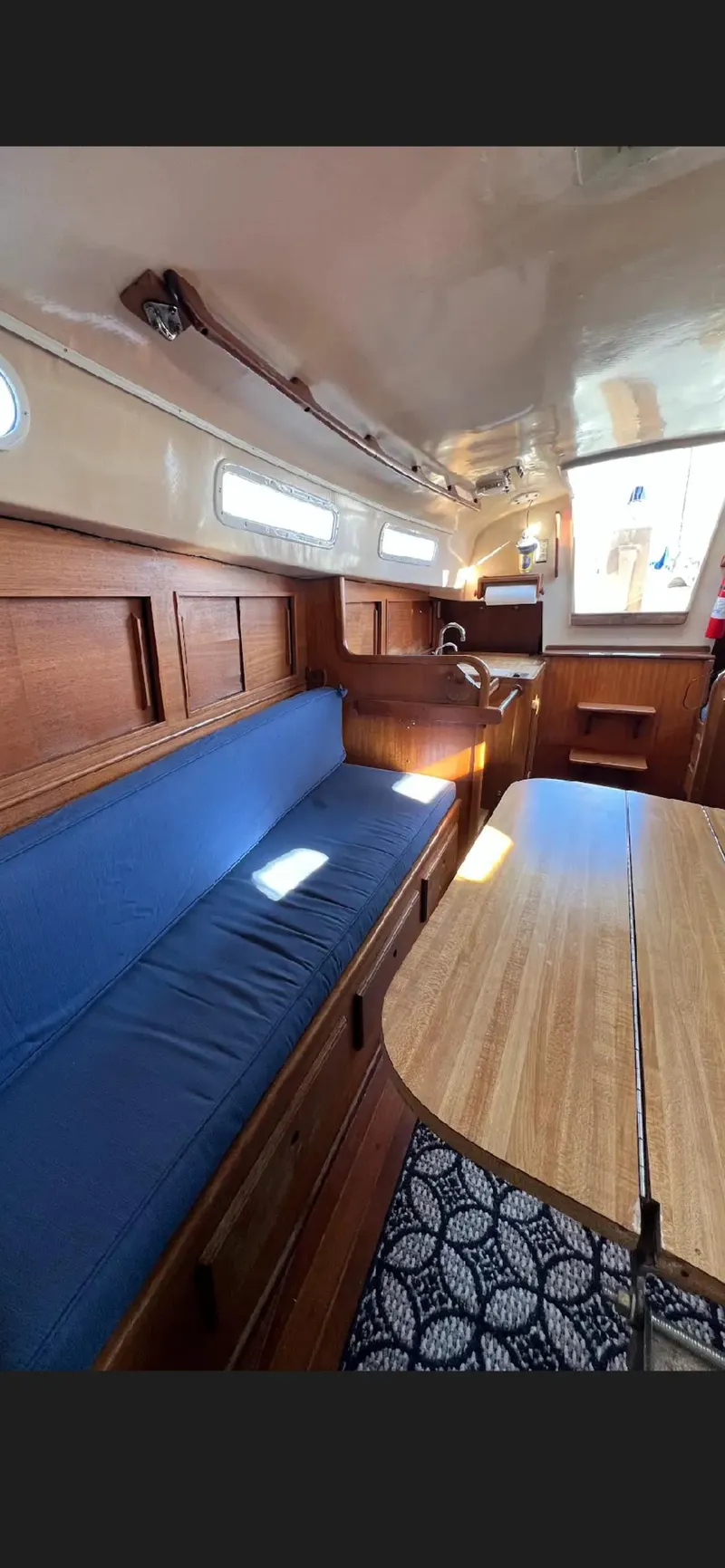 Slide: The Image of 1975 Bristol 34 yacht interior with wooden furnishings and blue cushioned seating. - 11