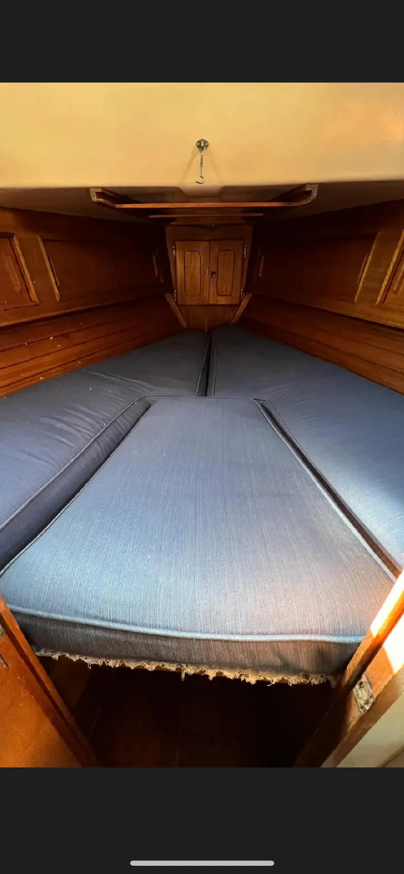 Slide: The Image of 1975 Bristol 34 sailboat interior cabin with blue cushions and wooden storage. - 14